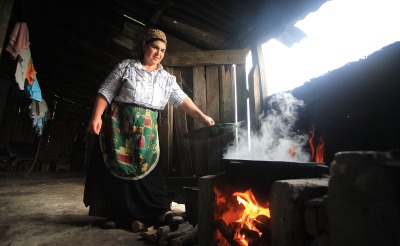 A woman cooks over an open flame in her home.